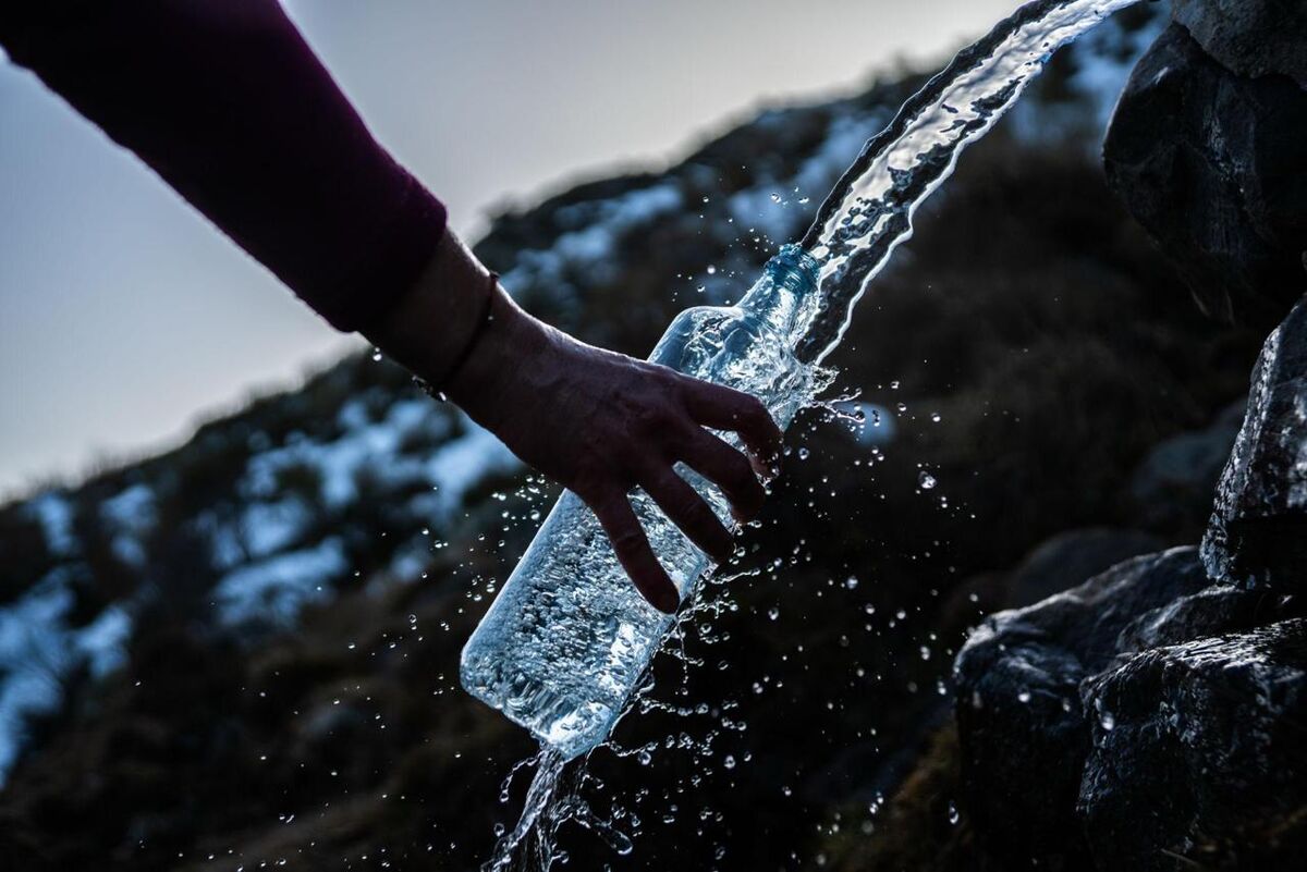 Hand filling bottle at mountain spring